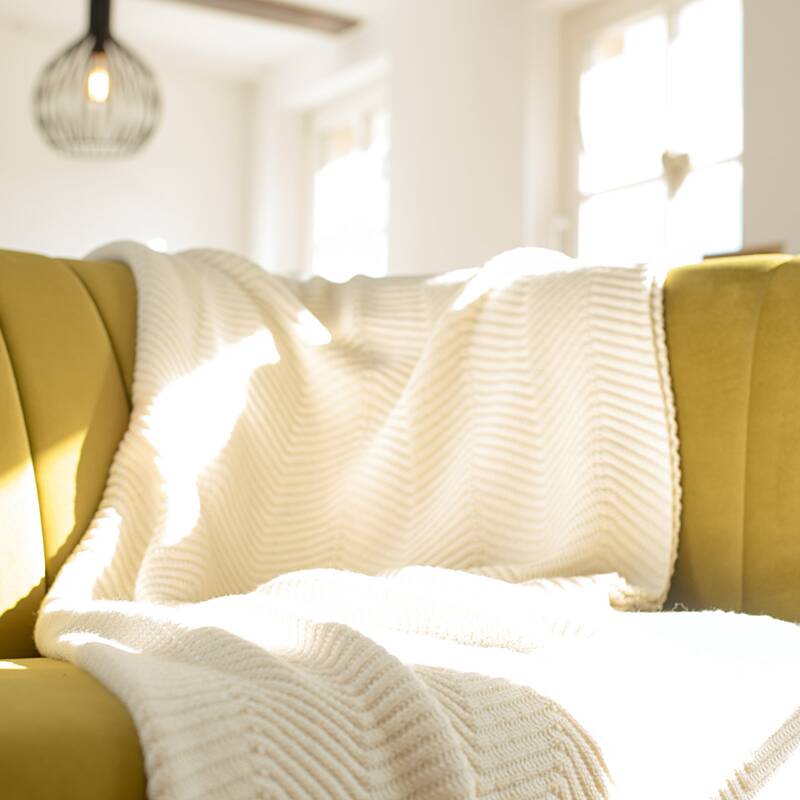 Produktfoto einer Decke mit Fischgrät-Muster von Sonnenstrick auf einem Sofa