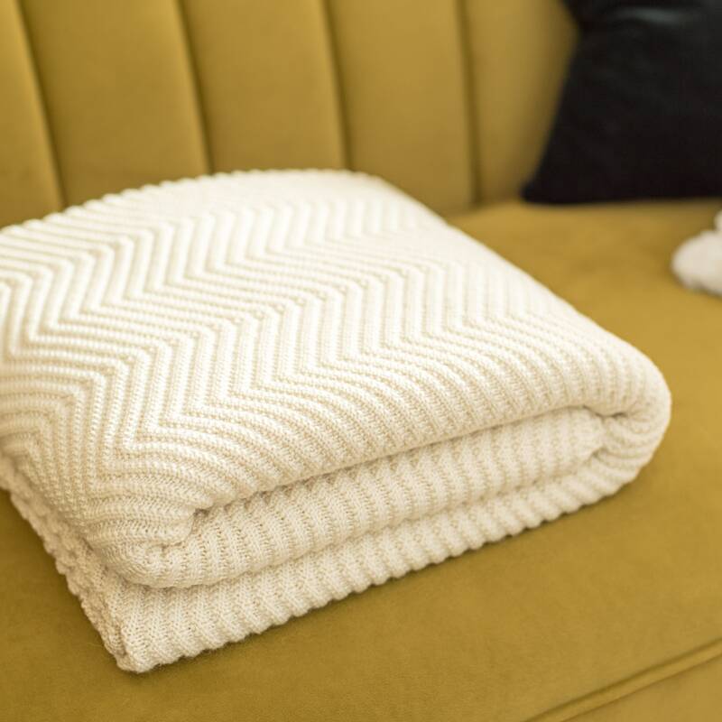 Produktfoto einer Decke mit Fischgrät-Muster von Sonnenstrick auf einem Sofa